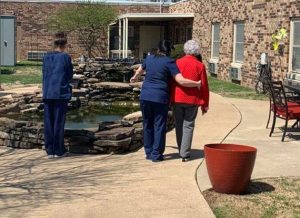 Nurse at Maranatha Village assisted living facility helping resident walk through courtyard