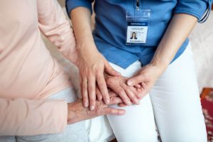 Senior and healthcare worker holding hands